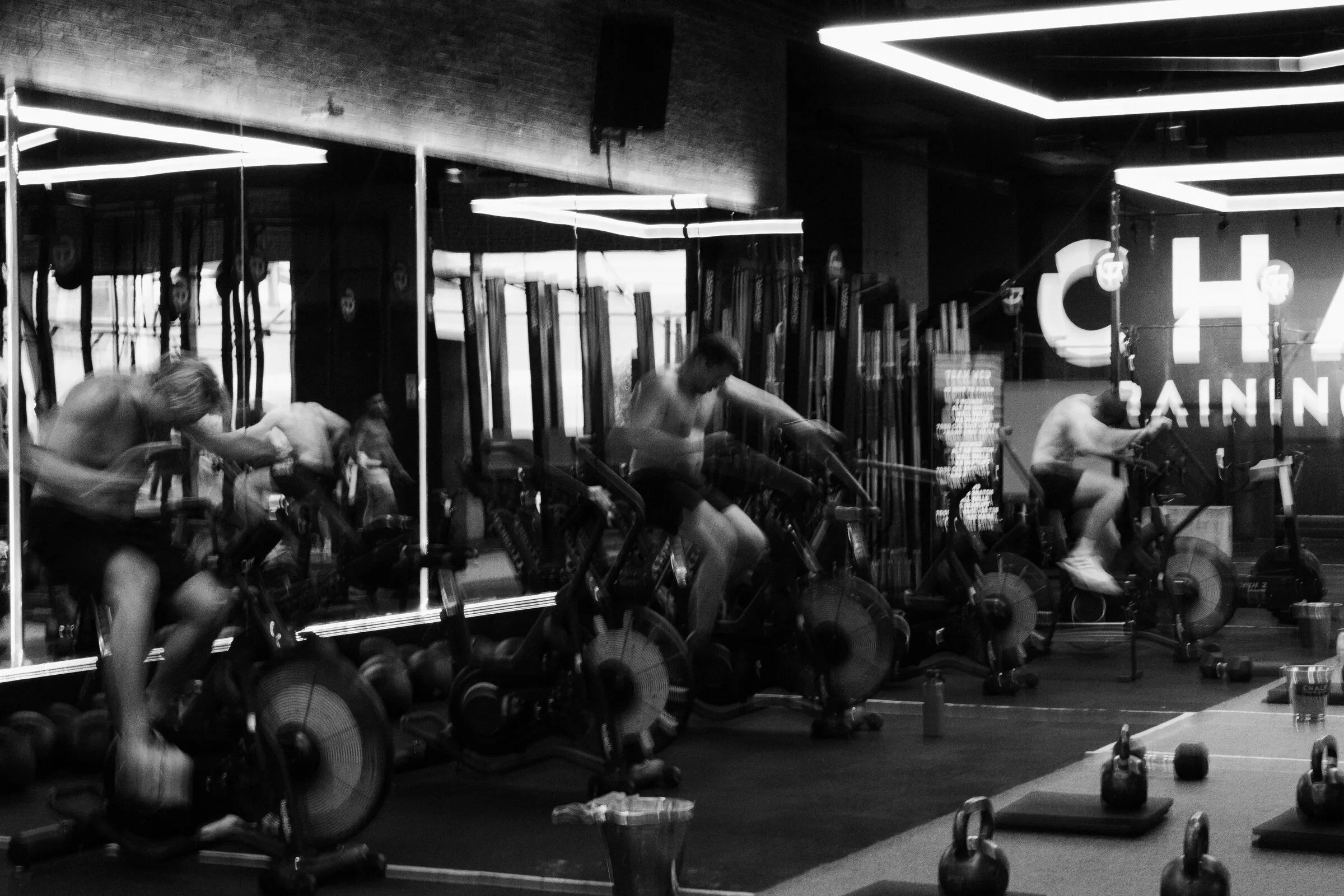 Athletes mid-effort on the assault bikes at Chalk Training Ground